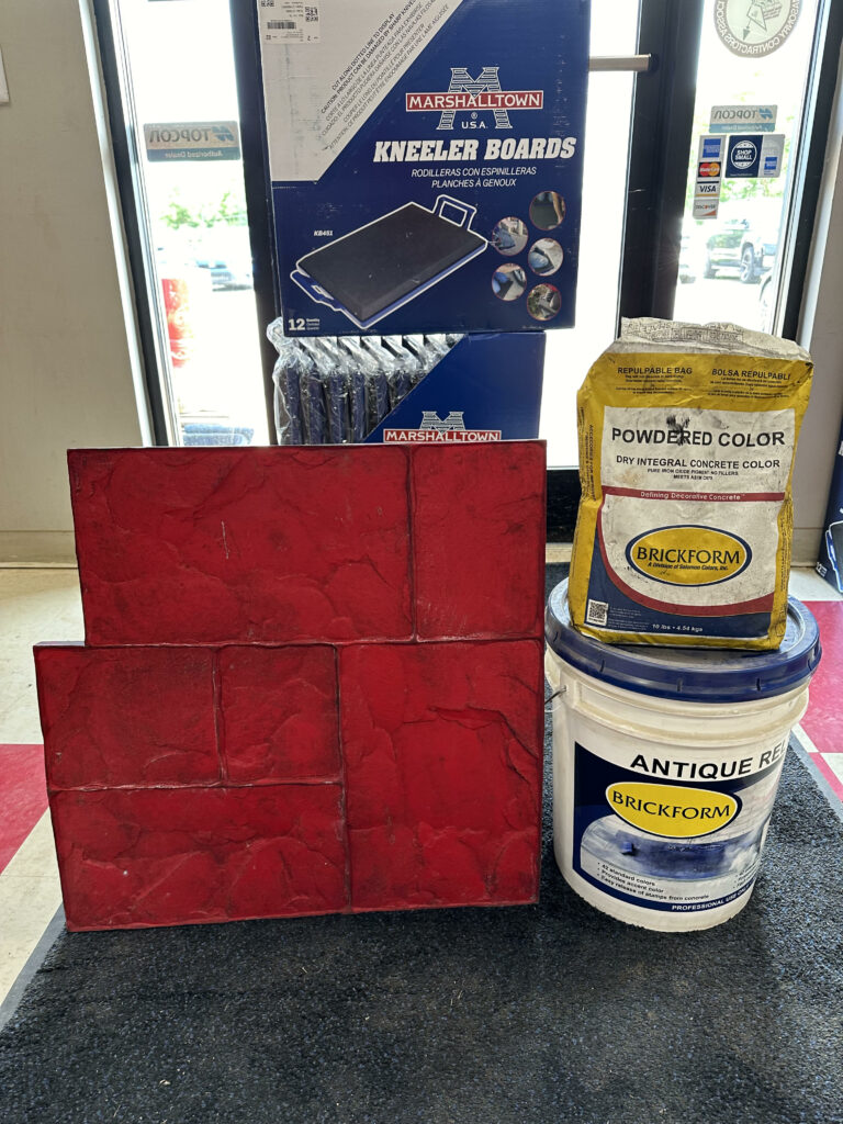 Red stamped concrete sample display with Brickform powdered colour, antique release, and Marshalltown kneeler boards in a decorative concrete showroom